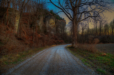 Down a Gravel Road at dusk by a large bluff  - obrazy, fototapety, plakaty