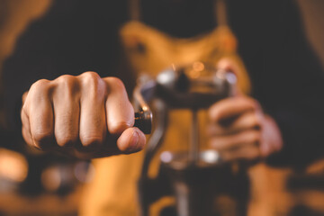 barista holding hand grinder to making beverage by grinding roasted coffee bean for caffeine drink in kitchen cafe background, morning breakfast mill preparation with espresso equipment in brown tone