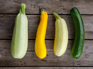 fresh mixed yellow, white, stripped and green zucchini's on a wooden background. Top view flat lay, close up