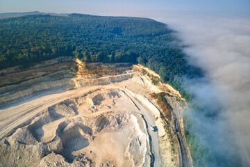 Aerial view of open pit mining of limestone materials for construction industry with excavators and dump trucks