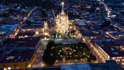 the church Parroquia Archangel Jardin Town Square Night Tree Decoraciones San Miguel de Allende, México. Parroaquia. Night and morning light in a drone view.