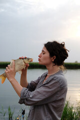 curly young girl on a fishing trip catches fish