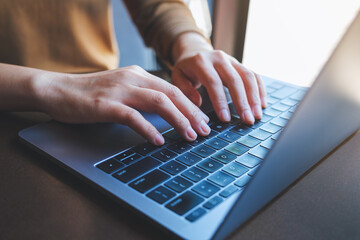 Closeup image of a woman working and typing on laptop computer keyboard