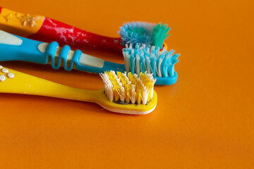 Old used multi-colored toothbrushes with curved bristles that need to be thrown away lie on an...