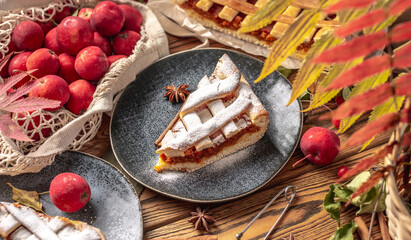 Appetizing homemade pie on a wooden table with garden apples, cinnamon and autumn leaves. Concept of a cozy atmosphere and autumn mood