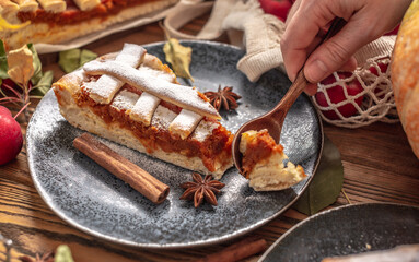 Hand of person is breaking off a piece of appetizing pie with a spoon. Concept of a warm and cozy autumn atmosphere with the aroma of fresh tasty pastries