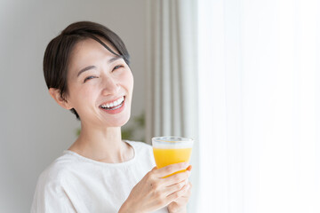 オレンジジュースを飲むミドル女性（健康・ヘルスケア）