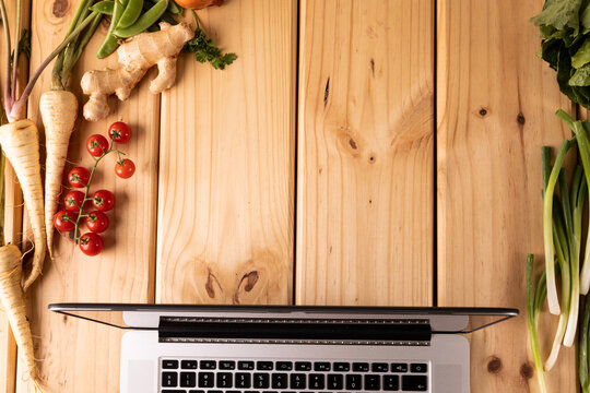 Directly Above Shot Laptop By Vegetables And Spices On Wooden Table With Empty Space