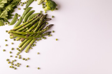 Overhead view of fresh asparagus and broccoli by copy space on white background