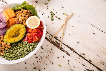 High angle view of fresh meal in bowl by scattered peppercorn on white wooden table