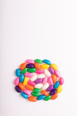 Directly above view of colorful candies arranged in circle with copy space against white background