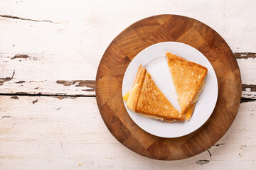 Directly above view of fresh cheese sandwich served in plate on wooden board over white table