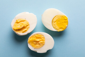 Overhead view of fresh boiled white egg halves on blue background