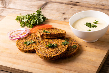 High angle view of fresh patties with dip bowl served on wooden serving board
