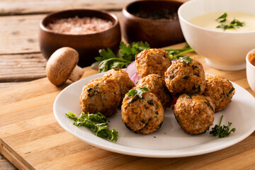 Close-up of fresh meatballs with edible mushroom and dip bowl on cutting board