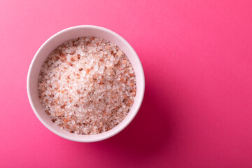 Directly above shot of himalayan salt in bowl on pink background with copy space - obrazy, fototapety, plakaty
