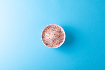 Directly above shot of himalayan salt in bowl over blue background with copy space