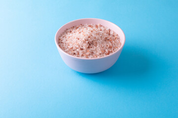 High angle view of himalayan salt in bowl on blue background with copy space