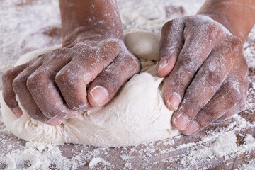 Fototapeta premium Close up view of hand kneading flour dough with copy space