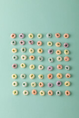 Directly above shot of colorful ring shaped breakfast cereal arranged on green background