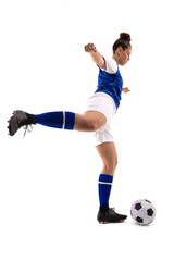 Side view of biracial young female soccer player kicking soccer ball while playing soccer
