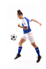 Side view of biracial young female player in mid-air kicking ball while playing soccer