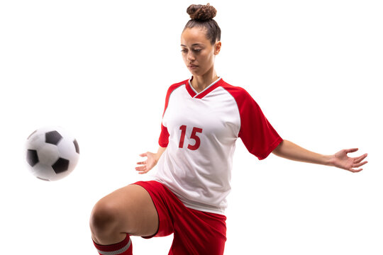Biracial young female soccer player kicking soccer ball with knee while playing on white background