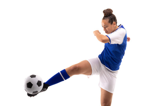 Full length of biracial young female soccer player kicking soccer ball while playing soccer
