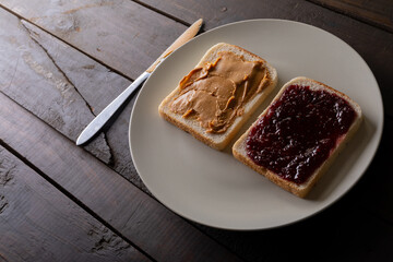 High angle close-up of preserves and peanut butter on bread slices served in plate at table