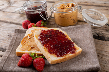 Open face peanut butter and jelly sandwich on napkin with jars and strawberries at table © wavebreak3