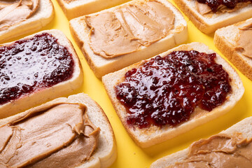Full frame shot of bread slices with preserves and peanut butter arranged on yellow background - Powered by Adobe