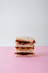 Stack of peanut butter and jelly sandwiches on table against gray background with copy space