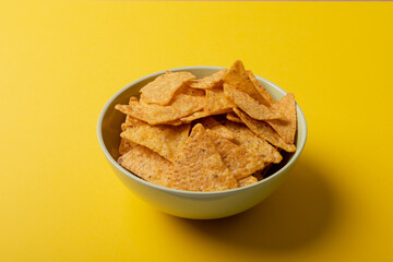 Close-up of nacho chips in bowl over yellow background