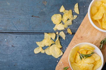 Foto op Plexiglas Directly above shot of potato chips in bowl with rosemary on serving board at wooden table © wavebreak3