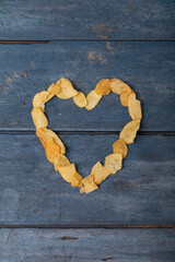 Overhead view of potato chips arranged in heart shape on wooden table
