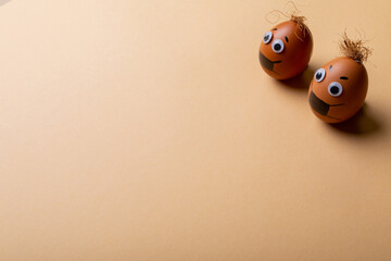 High angle view of easter eggs with face mask drawing and strings on top against orange background