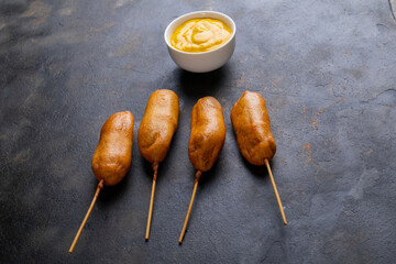 High angle view of corn dog with mustard sauce in bowl on table
