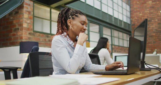 Happy african american businesswoman using laptop at office
