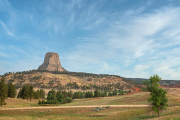 Devil's Tower National Monument in Wyoming from a distance showing blue sky with clouds and...