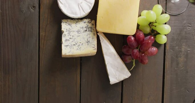Video of diverse cheeses, grapes and wine on wooden surface
