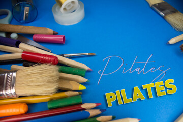 Overhead shot of school supplies with Pilates text. Brushes, pencils, artistic tools. Art And Craft Work Tools.
