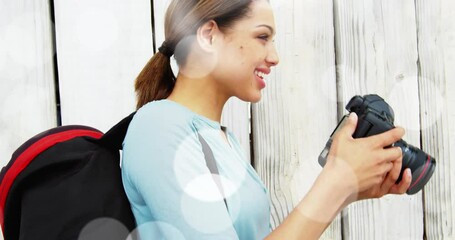 White spots floating against caucasian female photographer clicking pictures with digital camera