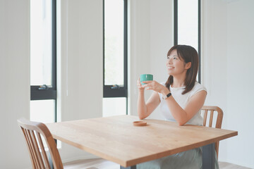 リビングで飲み物を飲んでリラックスする女性