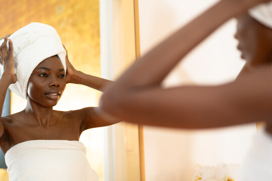 Fototapeta Reflection of african american young woman wearing towel on head in bathroom