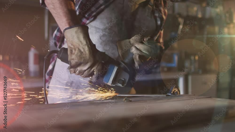 Poster animation of glowing light over caucasian man using grinder in workshop