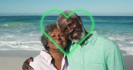 Animation of green hearts over african american senior couple on the beach
