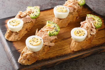 Avocado rye bread toast with tuna and boiled egg Healthy appetizer, breakfast, lunch or snack closeup on the wooden tray on the table. Horizontal