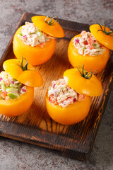 Traditional portuguese snack tomatoes stuffed with canned tuna and vegetables salad closeup on the wooden tray on the table. Vertical