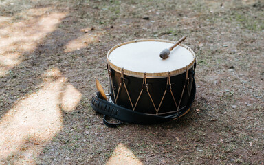 Medieval drum with drumstick lying on grass outdoors