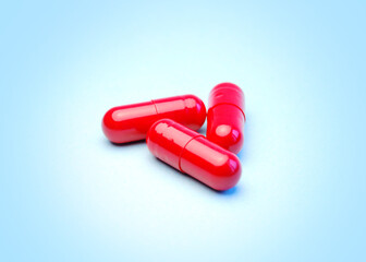 A group of three red capsules on light blue background
